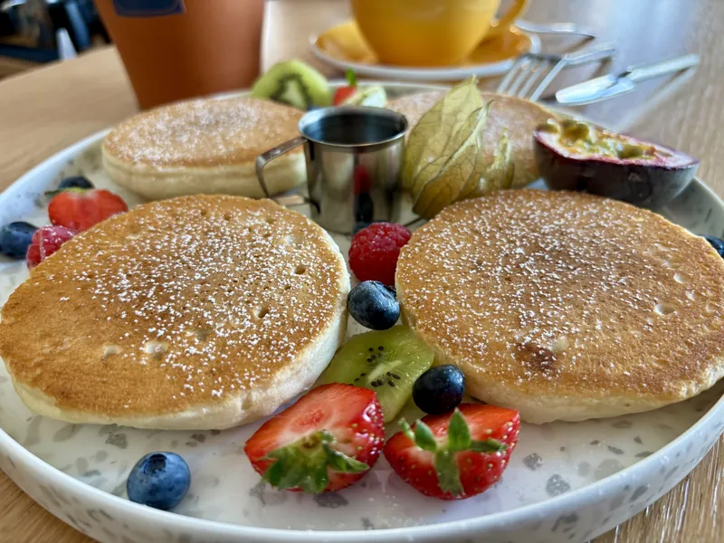 Pancakes mit Puderzucker, Erdbeeren, Blaubeeren, Kiwi und Maracuja